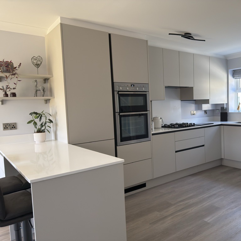 Small grey handleless kitchen Pale grey handleless kitchen with built in oven